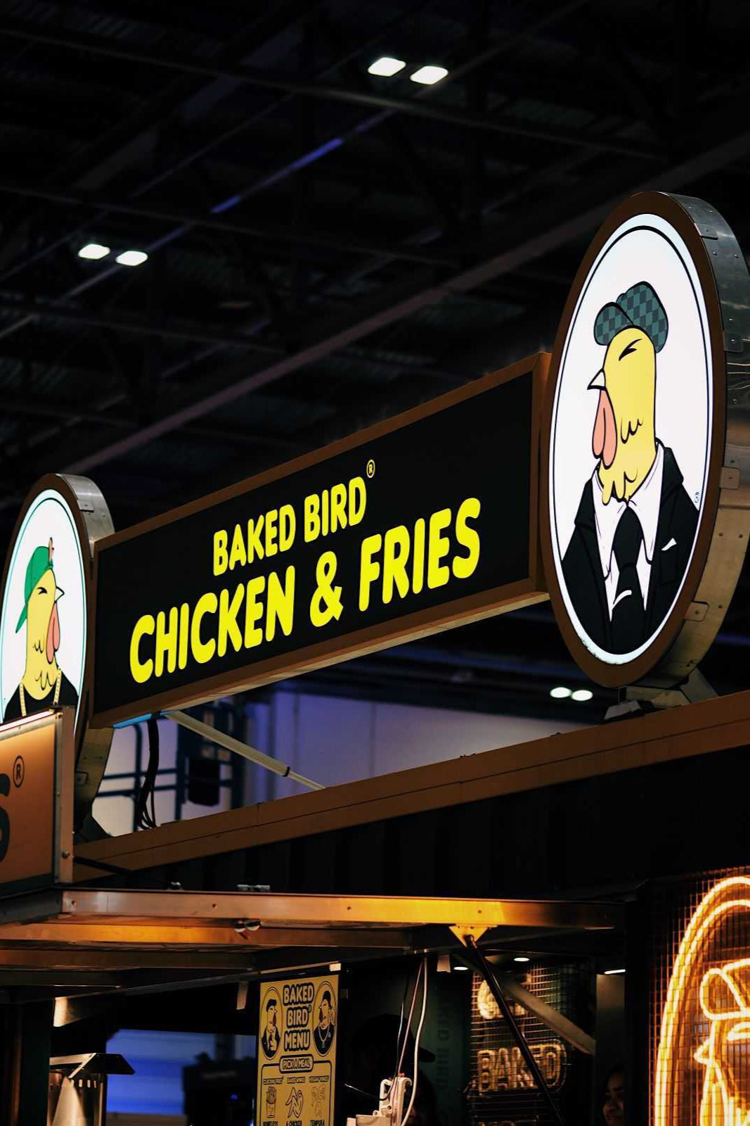 The illuminated signage of the BAKED BIRD® Bird Box 2.0 events truck, showcasing bold branding and signature yellow glow.