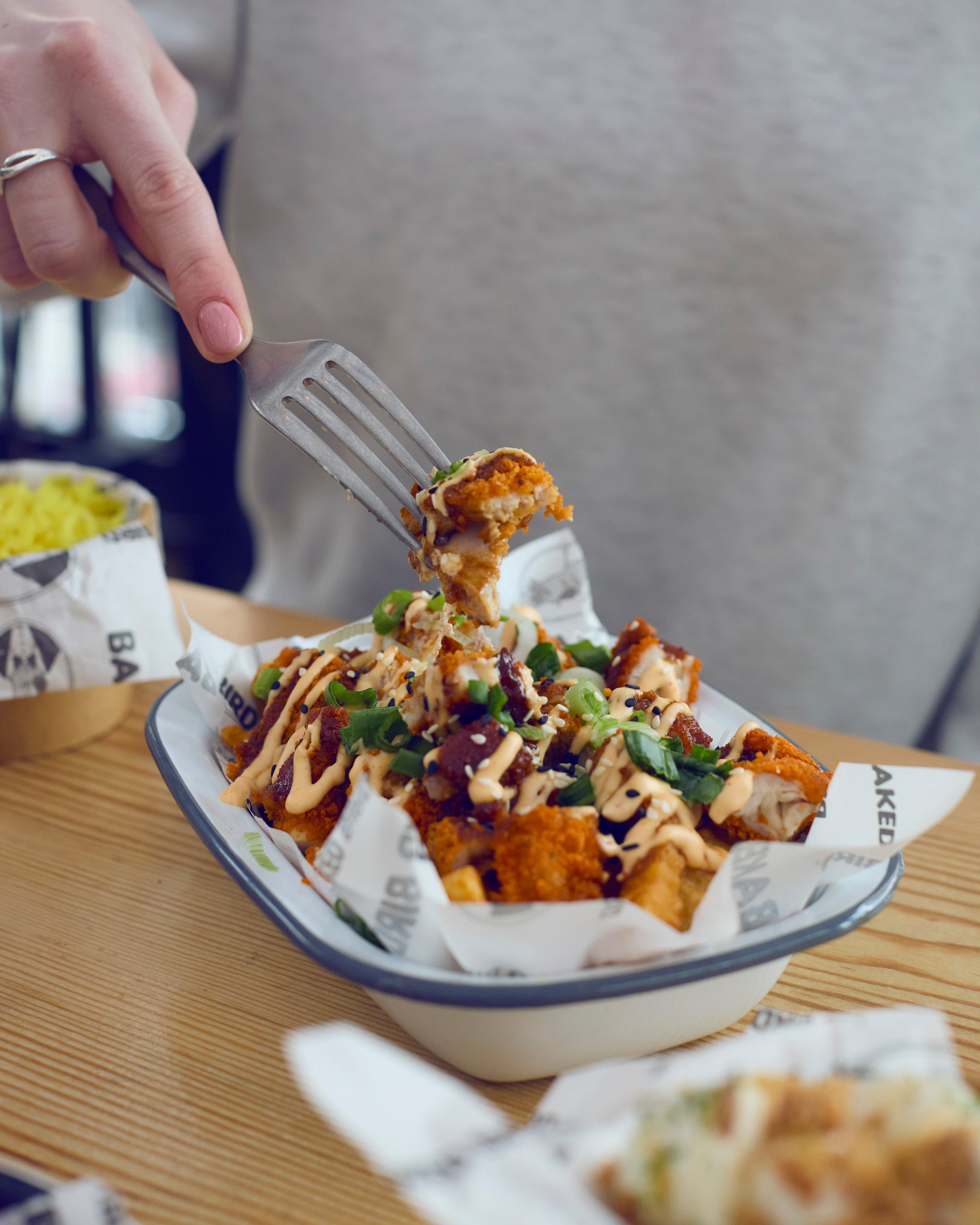 A close-up of our fries box, covered n our baked chicken wings, and topped with our award winning sauce.