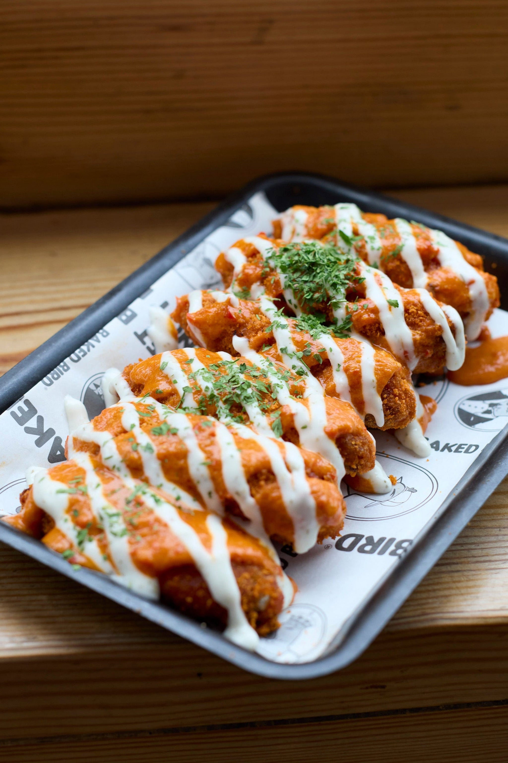 BAKED BIRD® oven-baked chicken wings, each coated in a different award-winning sauce, served fresh and ready to share.